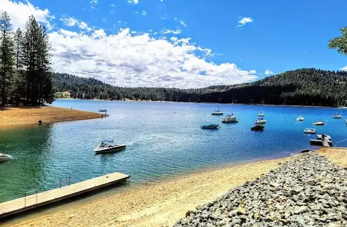 Boats moored off the sandy beach and dock at Scott's Flat Lake