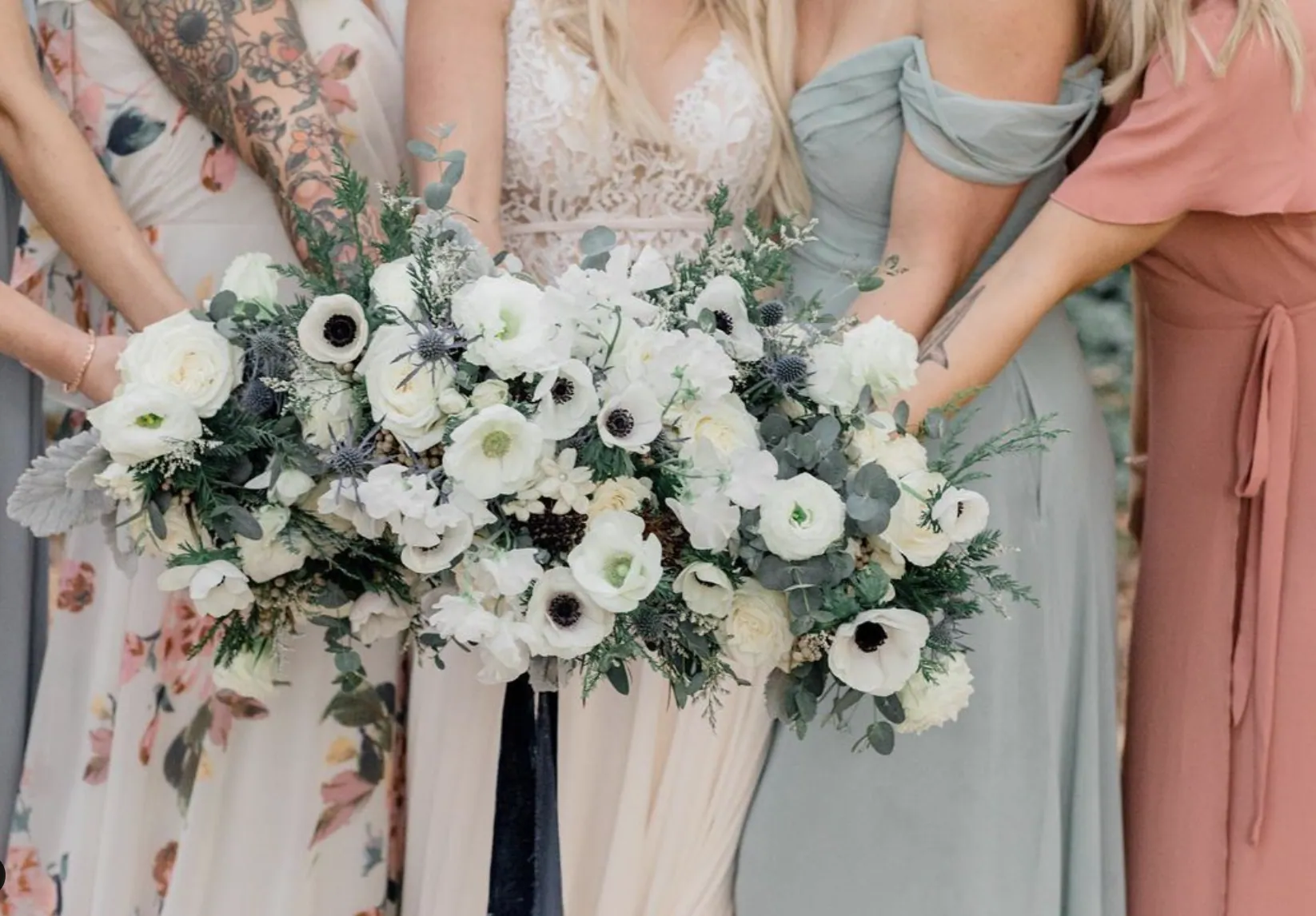A bride and her bridesmaids holding white anemone and eucalyptus bouquets