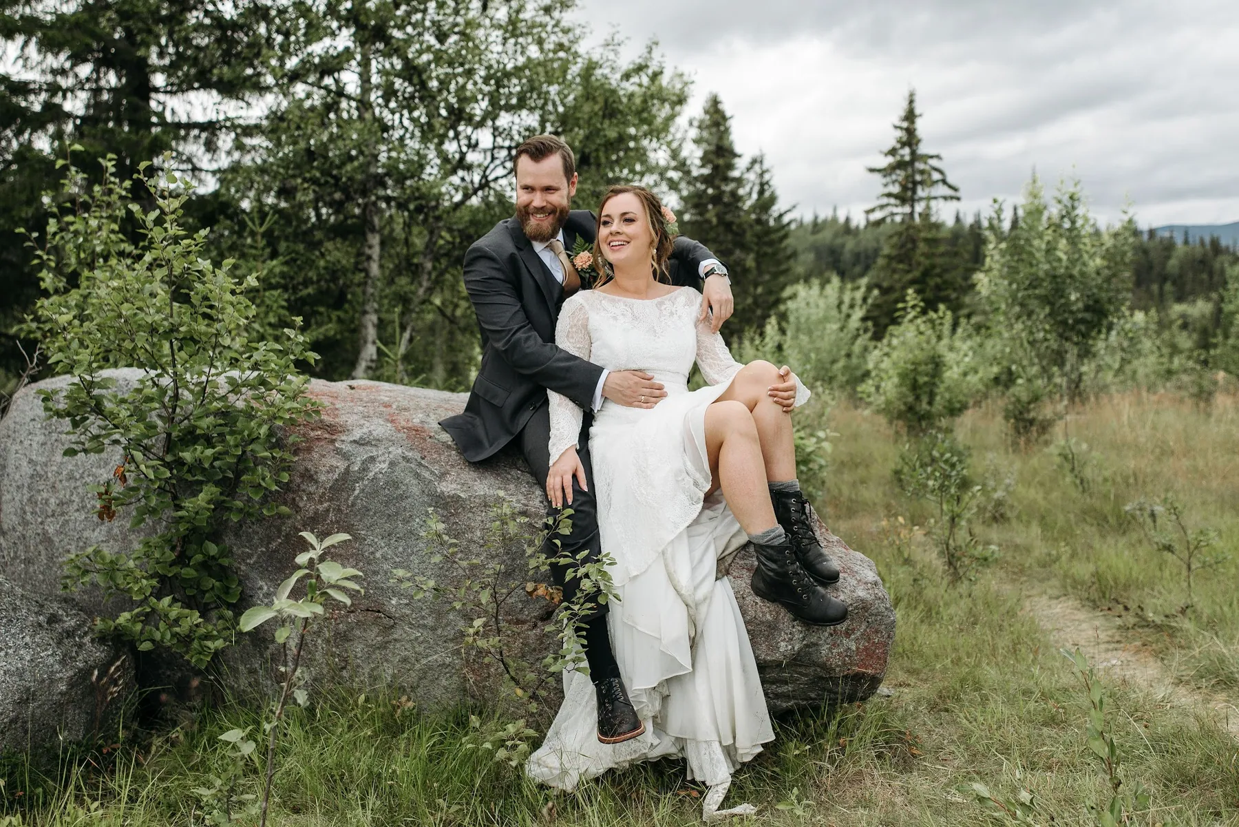 A couple seated on a granite boulder in the foothills, pines behind them