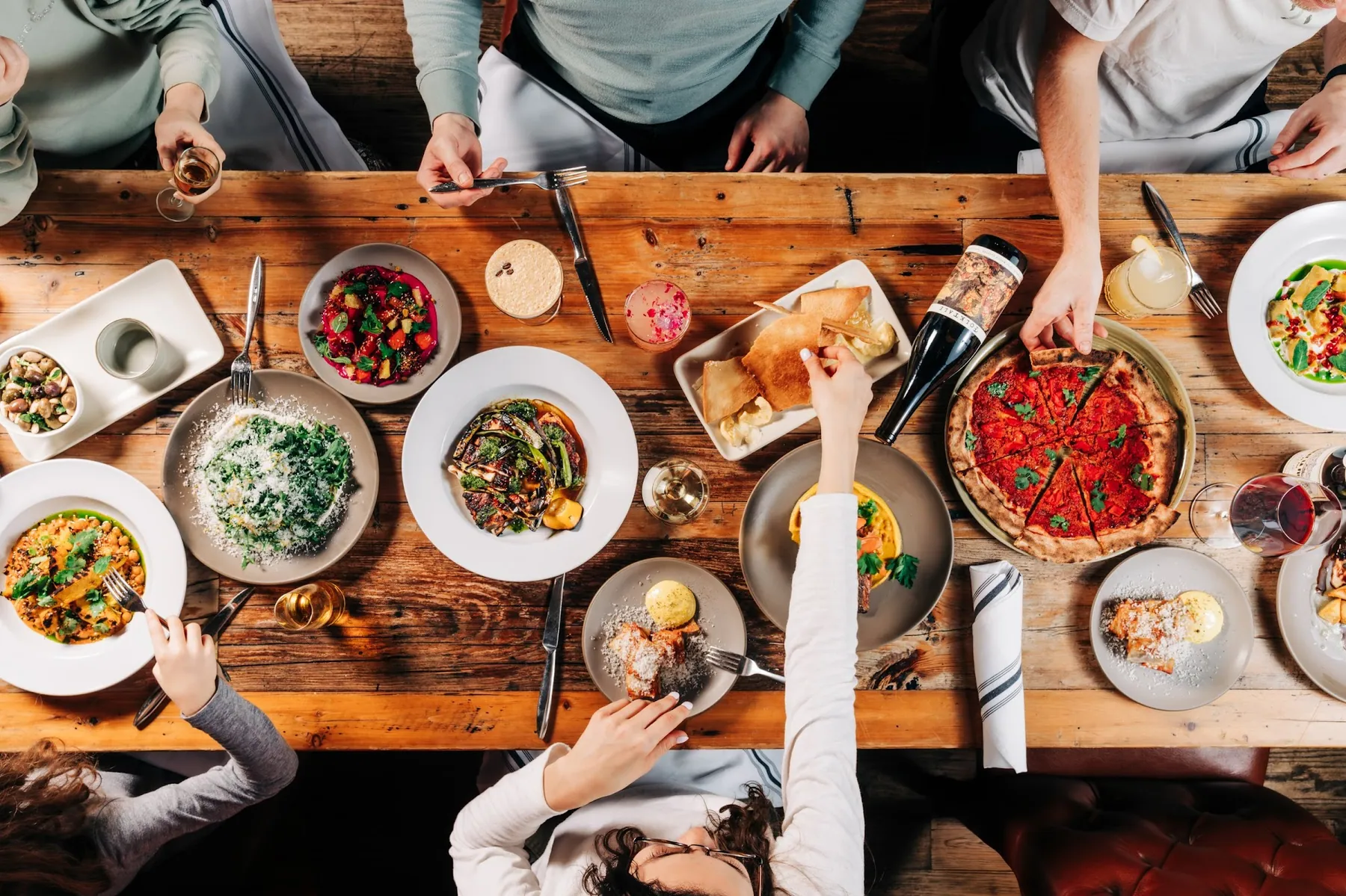 An overhead view of a shared family-style dinner spread across a long wooden table