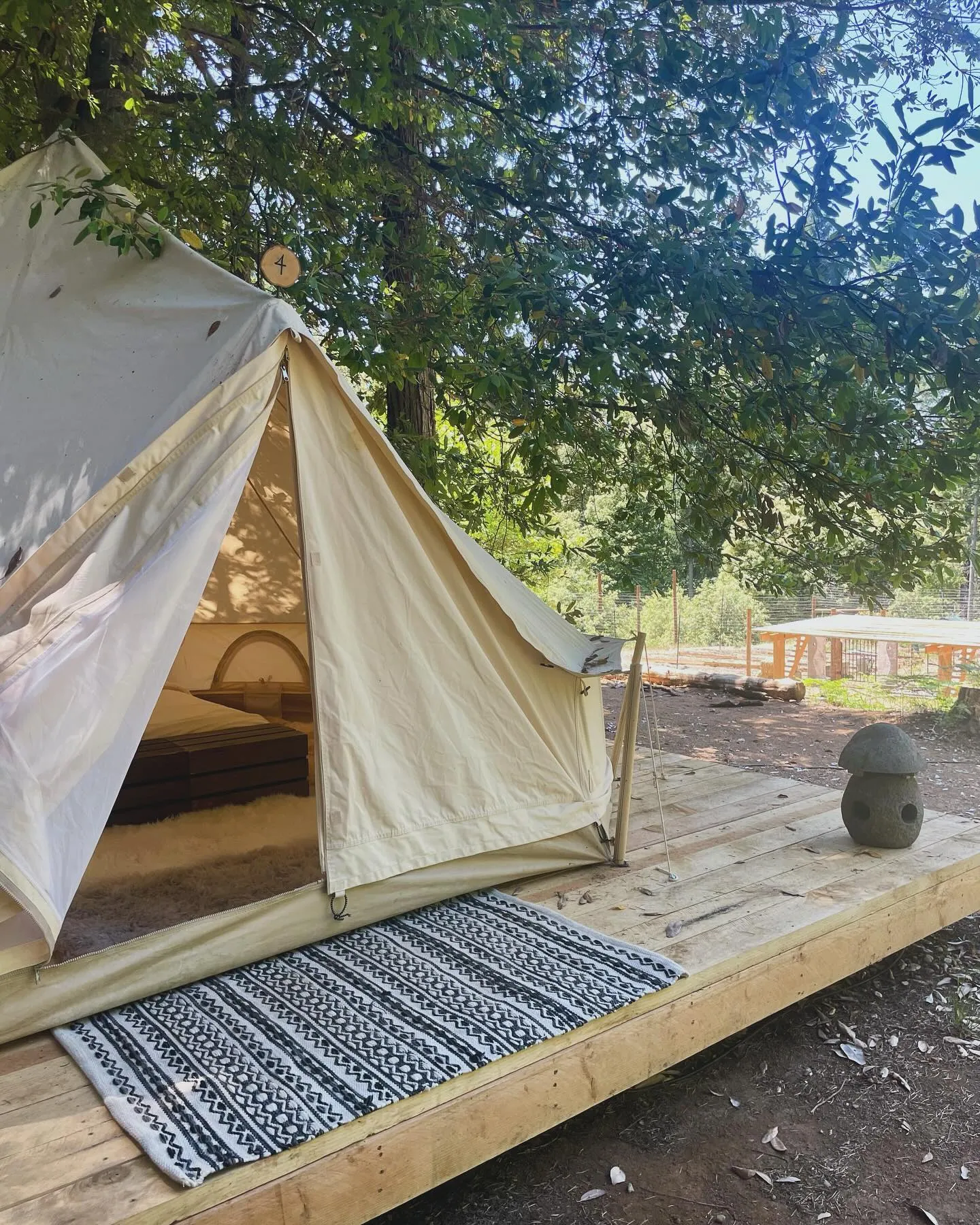 A bell tent with its doors open and a patterned rug at the entrance