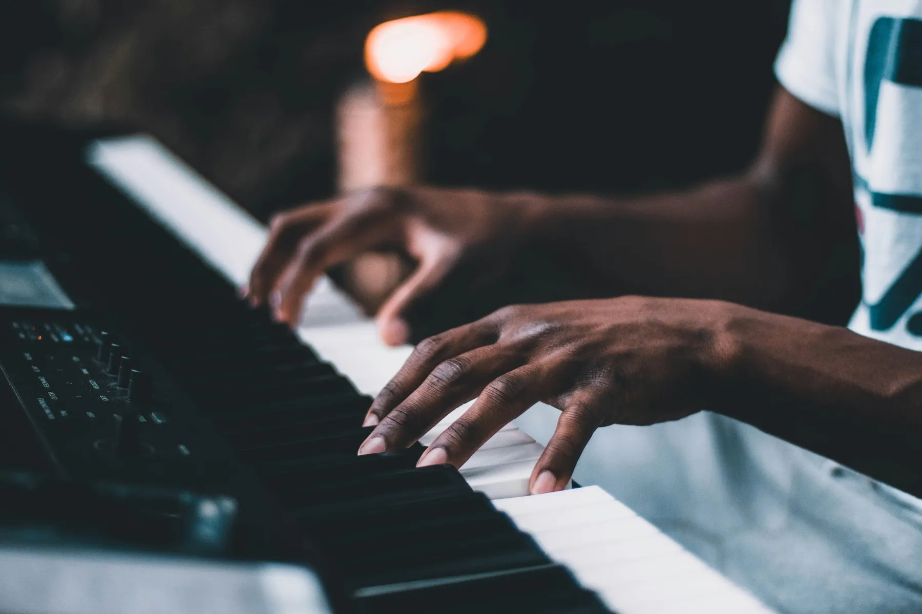 Hands moving across a keyboard by candlelight