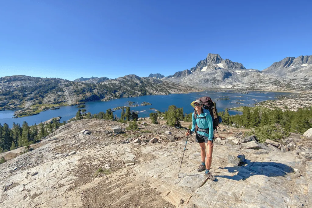 A hiker with a pack looking out over an alpine lake in the high country