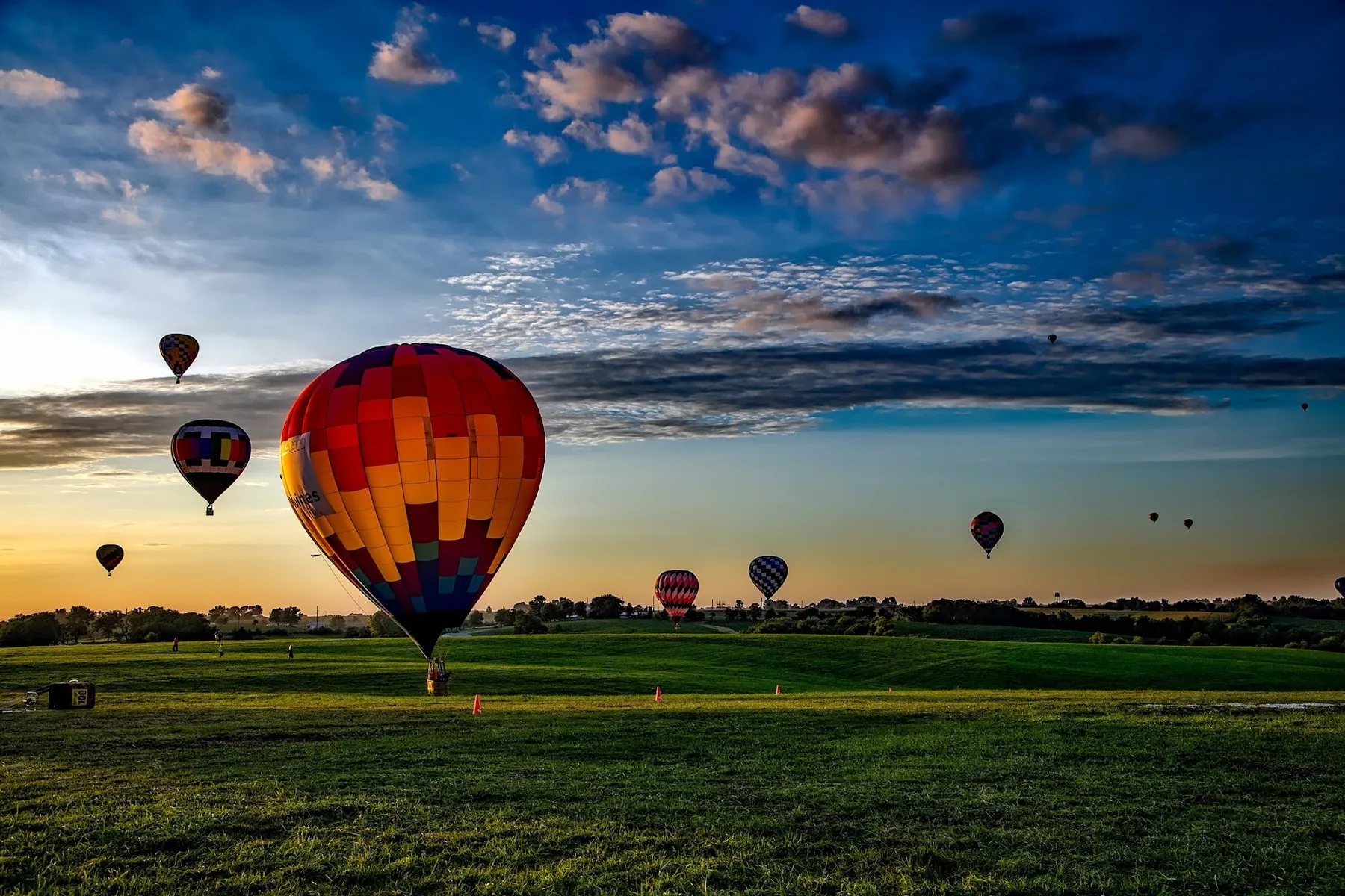 Hot-air balloons rising over open fields at dawn