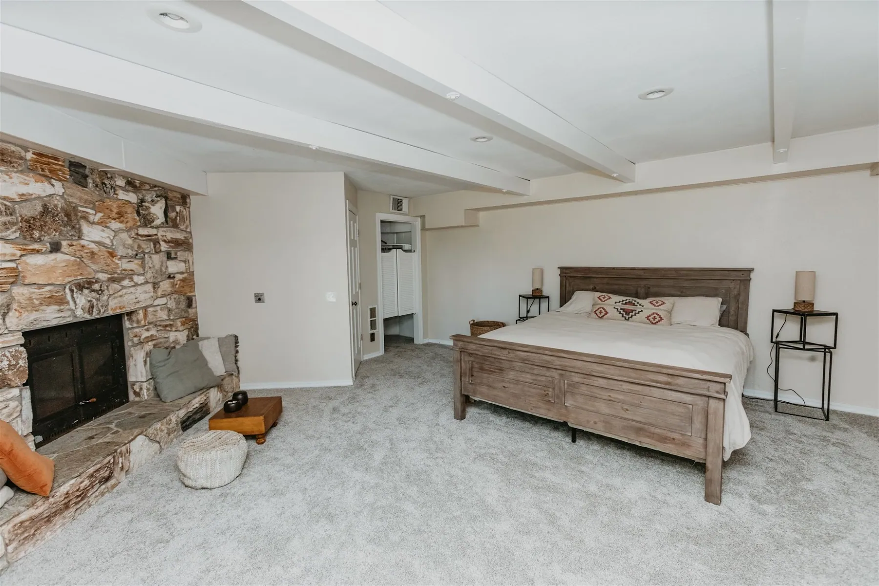 A bedroom with a stone fireplace and a carved wooden bed frame