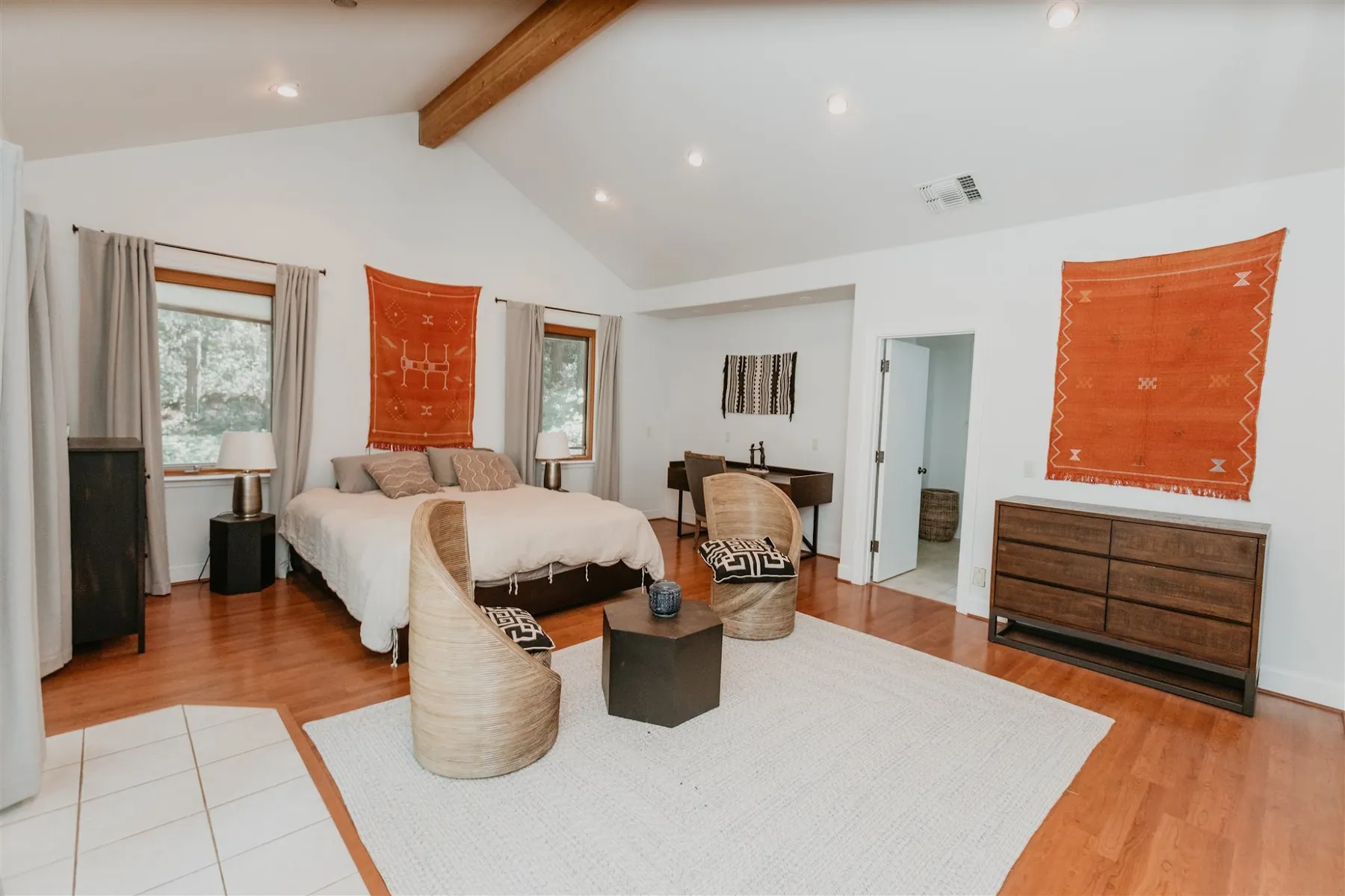 A lodge bedroom under vaulted ceilings, with warm textiles and windows to the forest