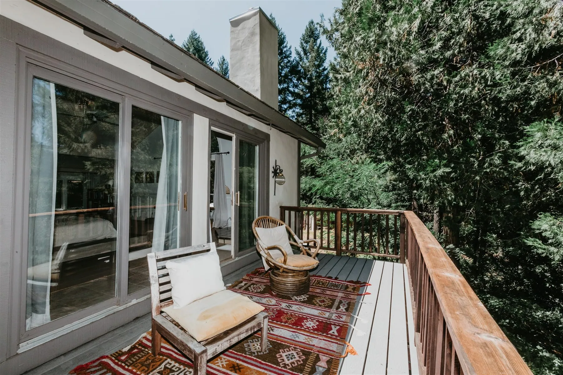 Deck seating with layered rugs outside the sliding doors, looking into the trees