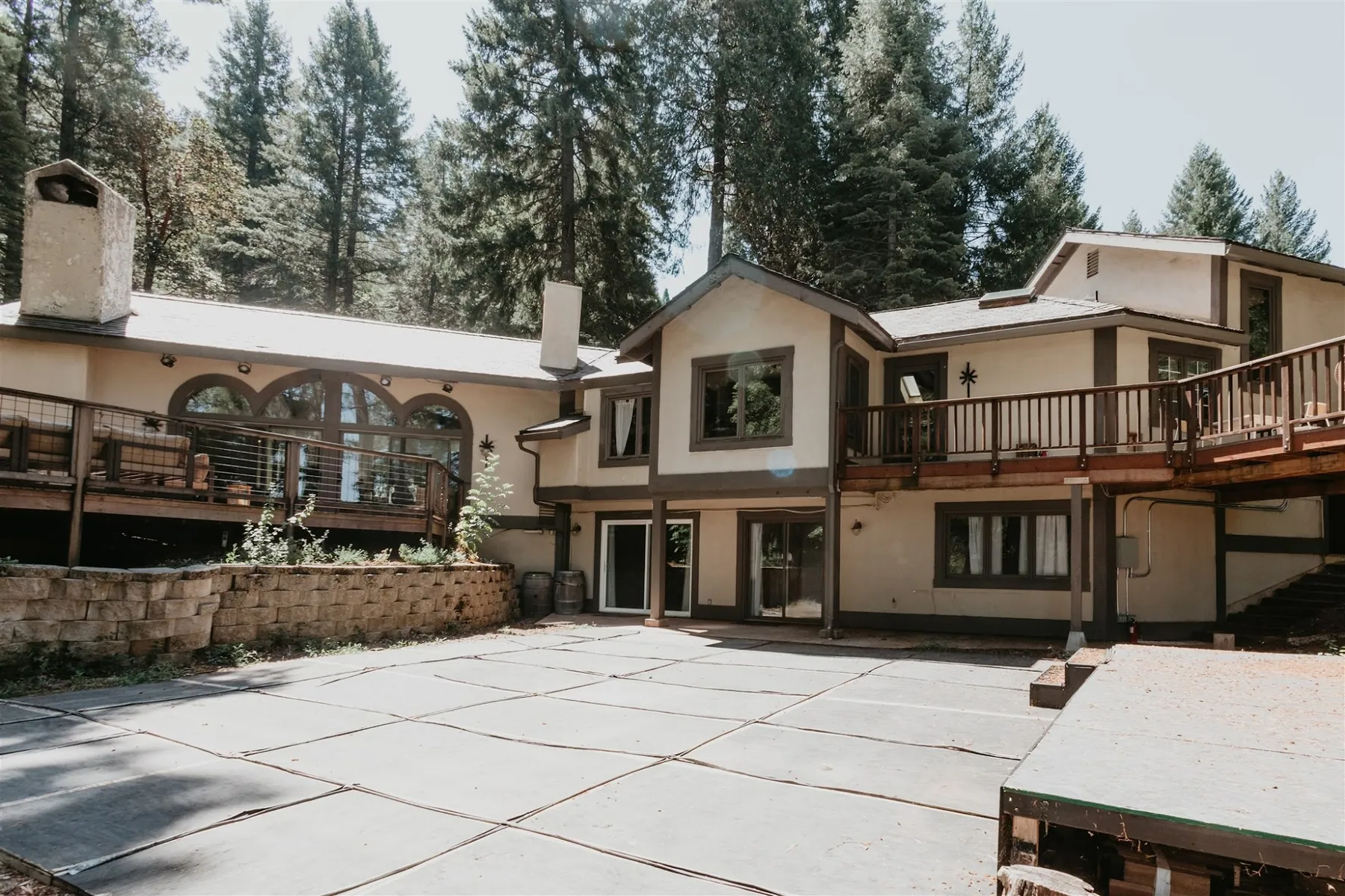 The lodge exterior with its wraparound deck and stone patio, set among tall pines
