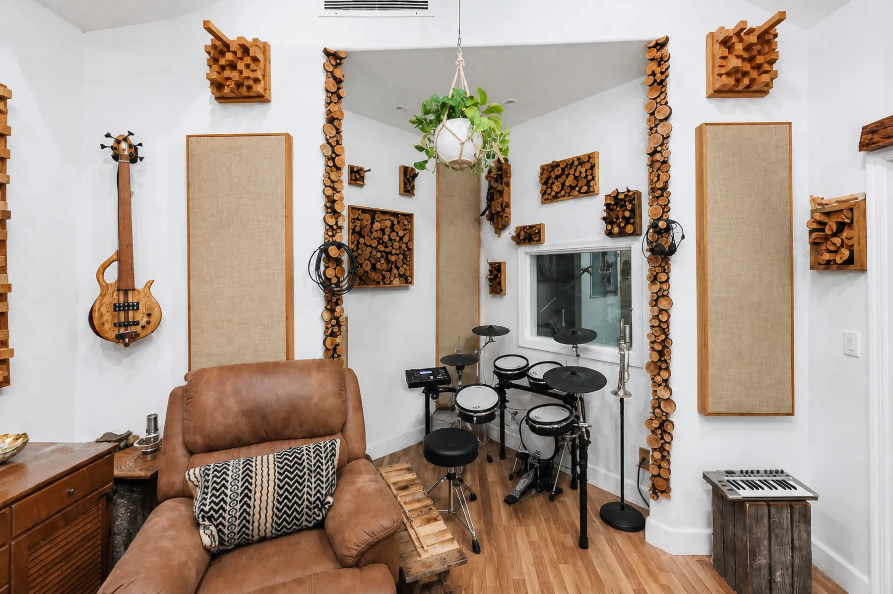 A corner of the studio with a bass guitar on the wall, drums and a worn leather armchair