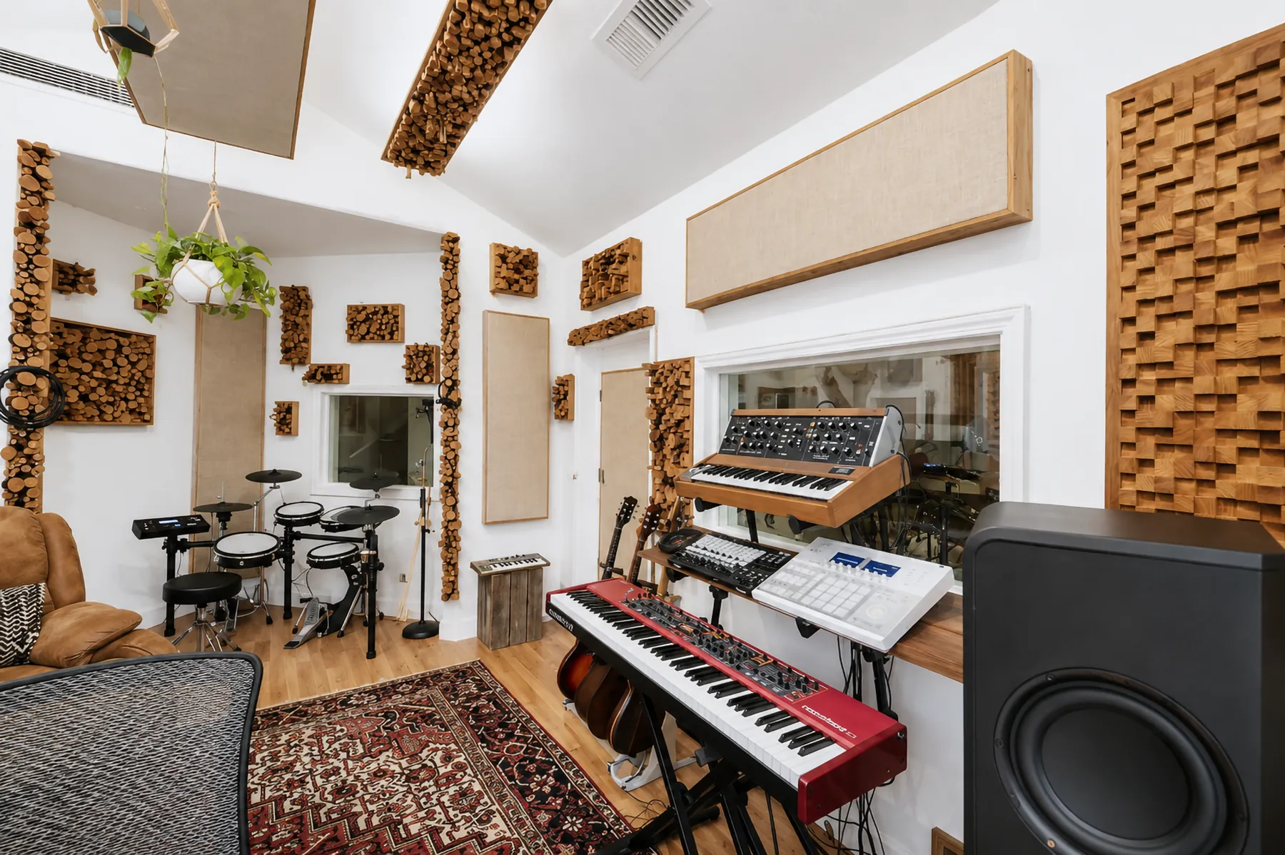 Synthesizers, keyboards and electronic drums set up against acoustic-treated walls