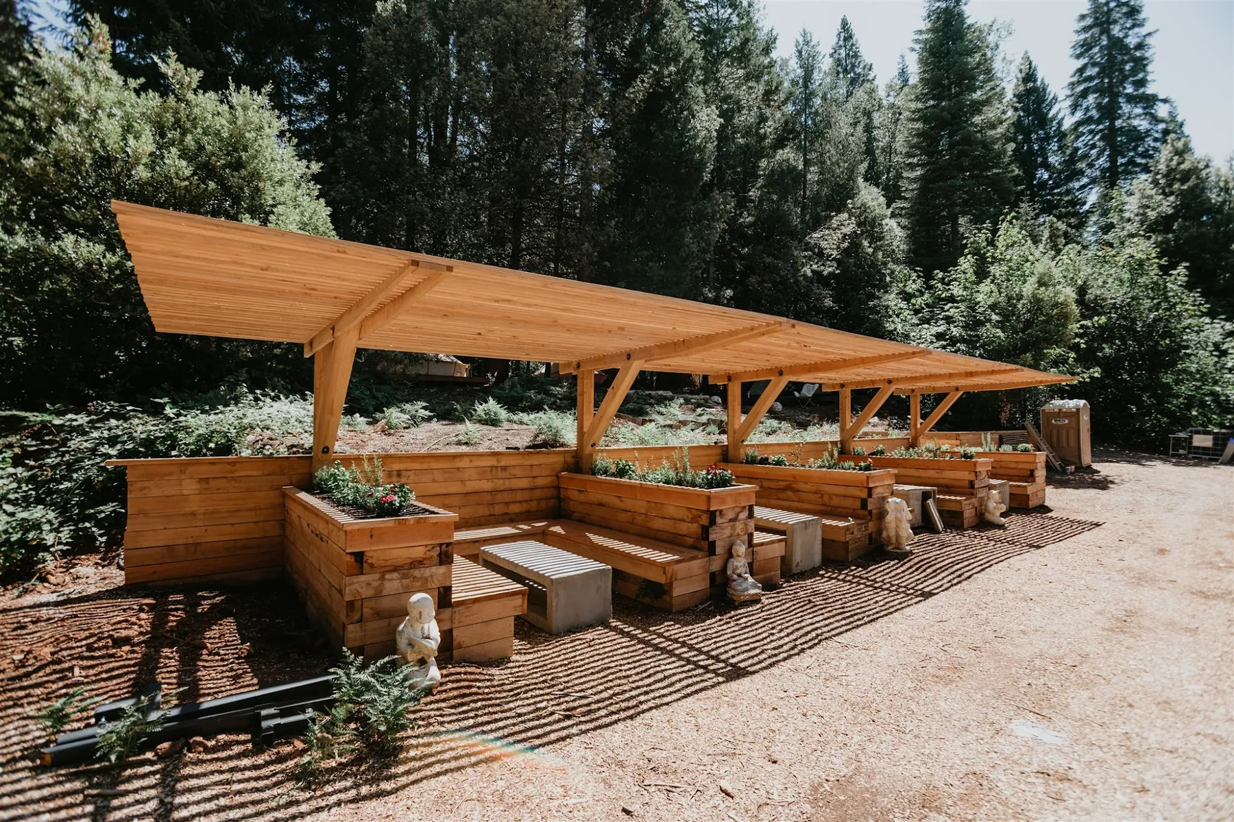 A long covered pergola with bench seating running beside the gravel path
