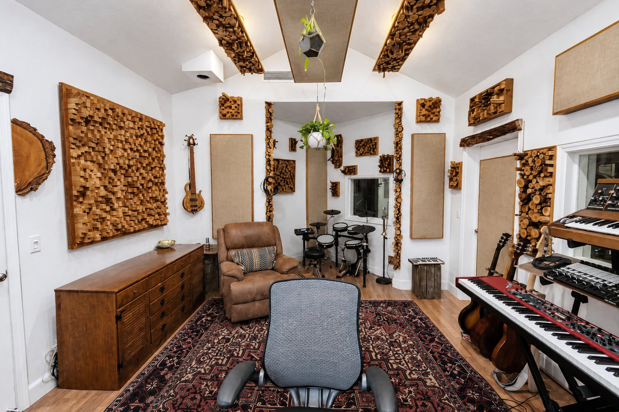 A carved wood diffuser panel above a sideboard, a listening chair facing the desk